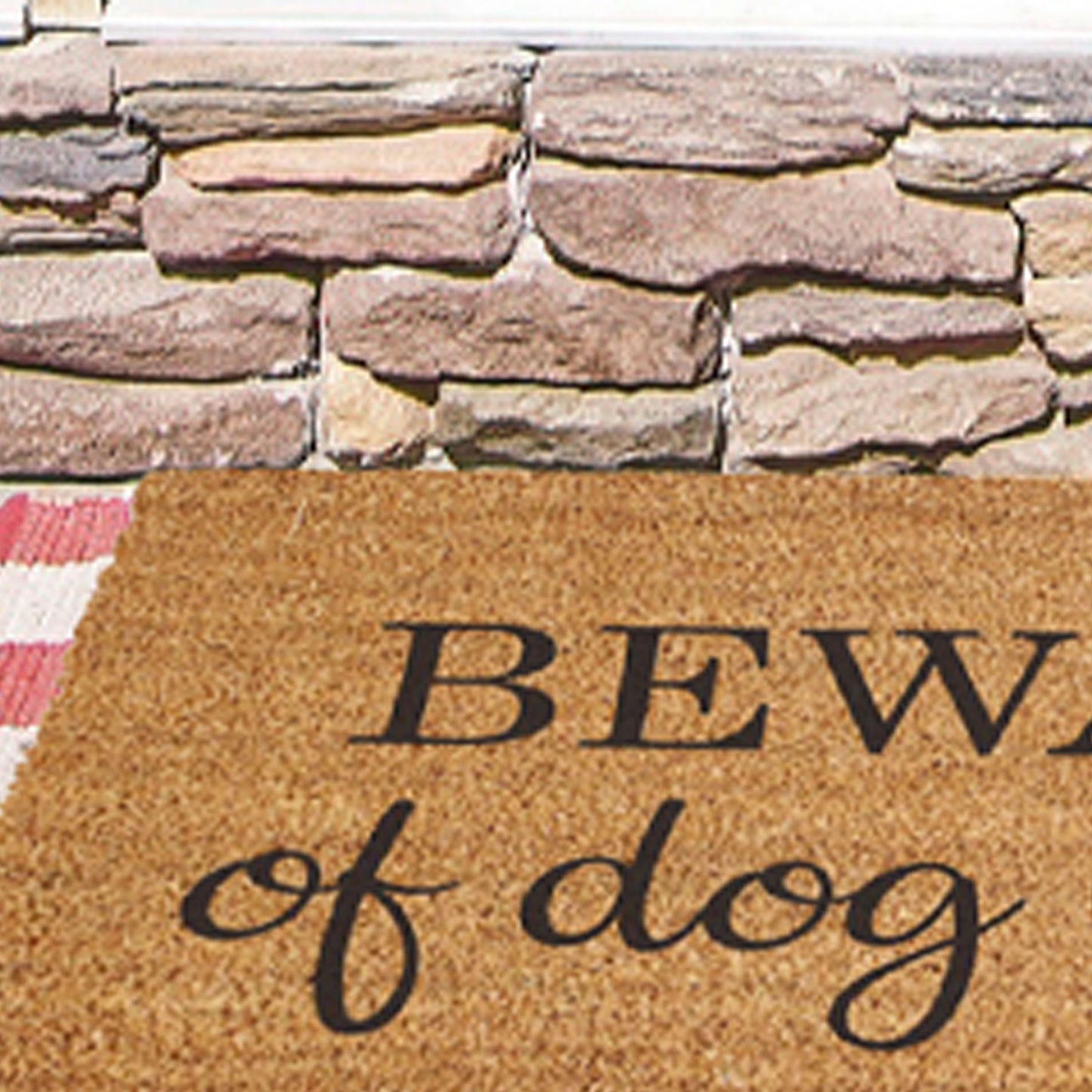 Zoomed in details of a coir doormat that has a fun hearted message: Beware of Dog Kisses, on it.